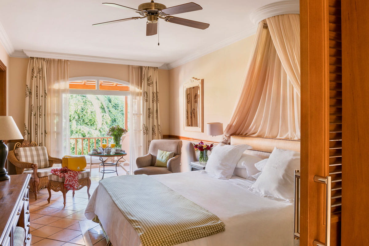 Room with a large bed, elegant furniture and garden view in Tenerife.