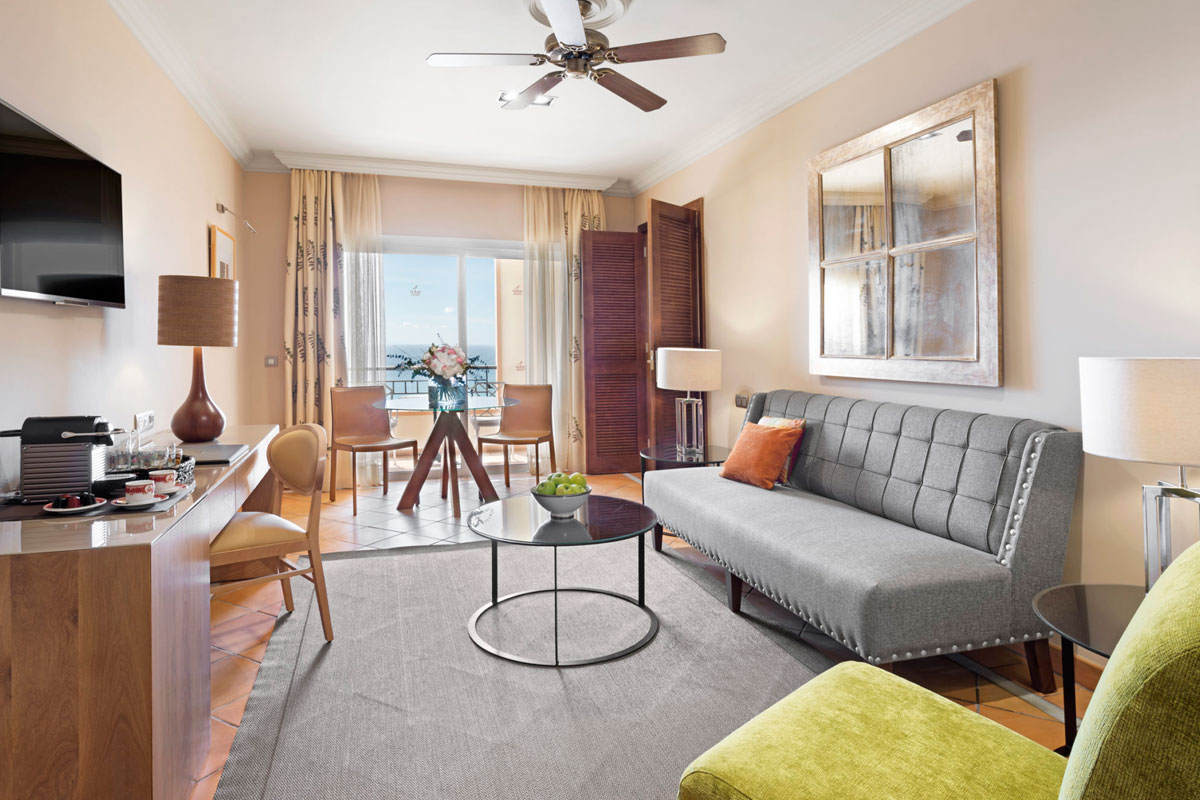 Living room with grey sofa, glass table and sea view in a hotel in Tenerife.