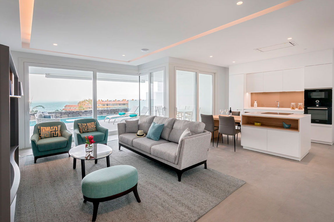 Modern living room with sea view in Tenerife, grey sofas and integrated kitchen.