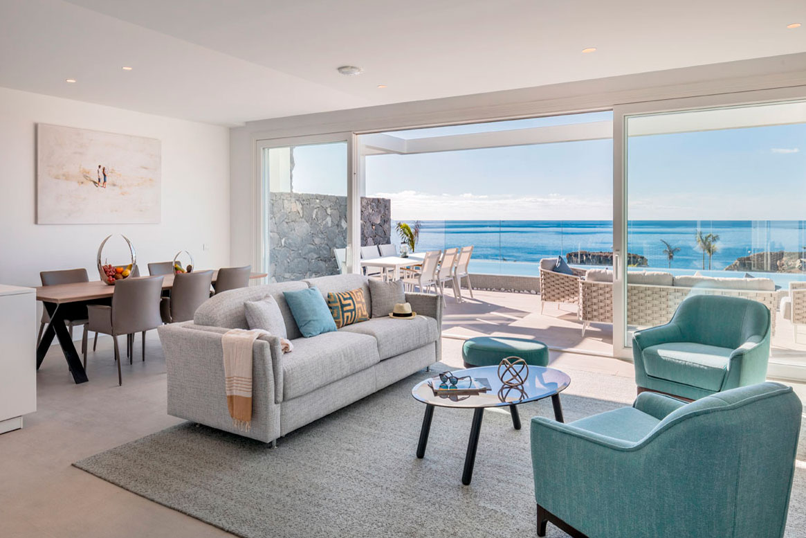 Modern living room with sea view in Tenerife. Grey sofa, blue chairs and table.