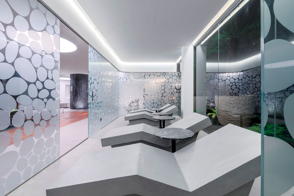 Relaxation room with sun loungers and glass walls with circle design in Tenerife.