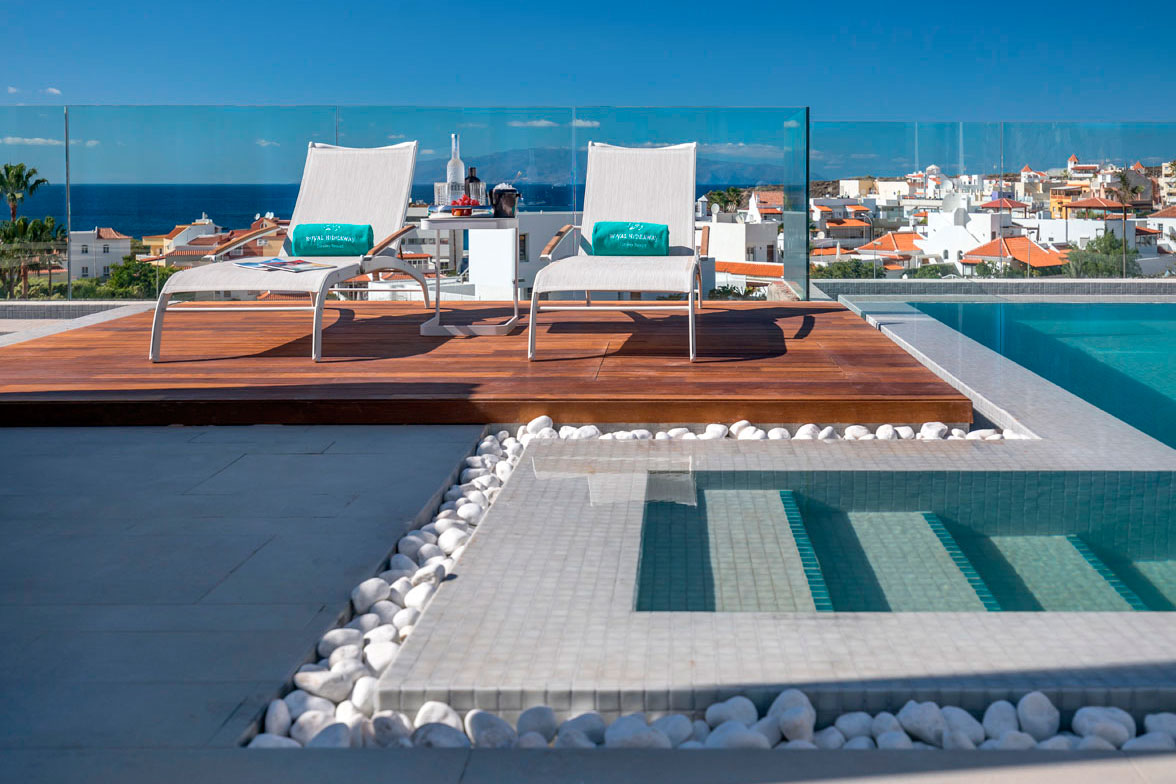 Sun loungers by a pool overlooking the sea and the city in Tenerife.