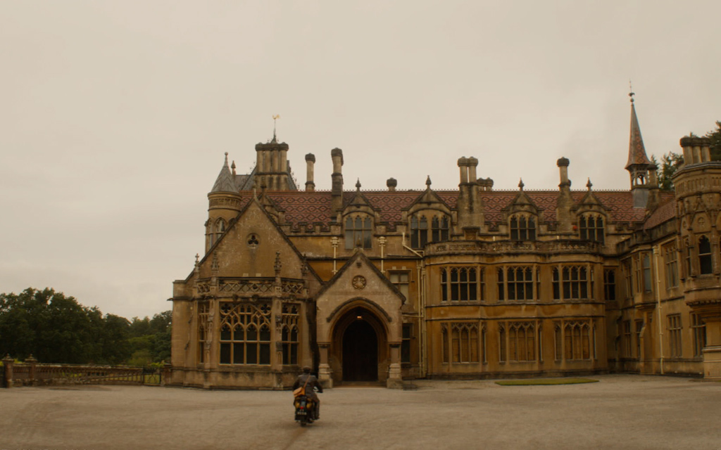 Old building with Gothic architecture and motorcycle in front of the entrance.