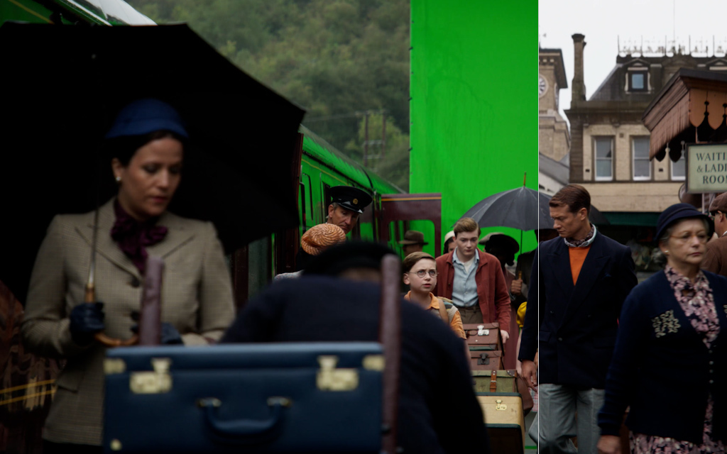 People with umbrellas and suitcases next to an old train at a station.