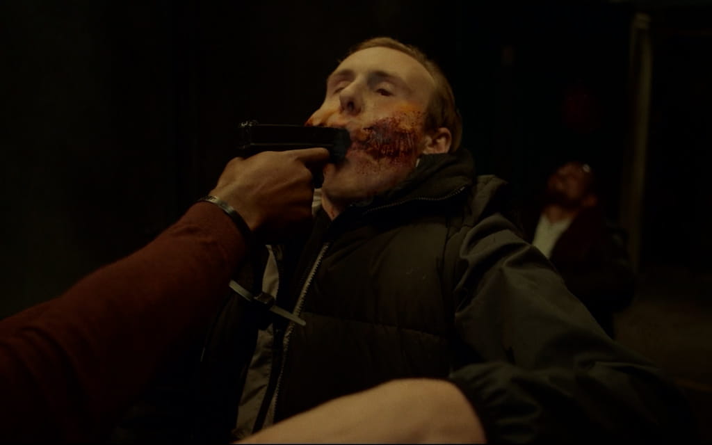 Cinematic scene with intense lighting and warm tones, centered on a character in the foreground with a blurred background.
