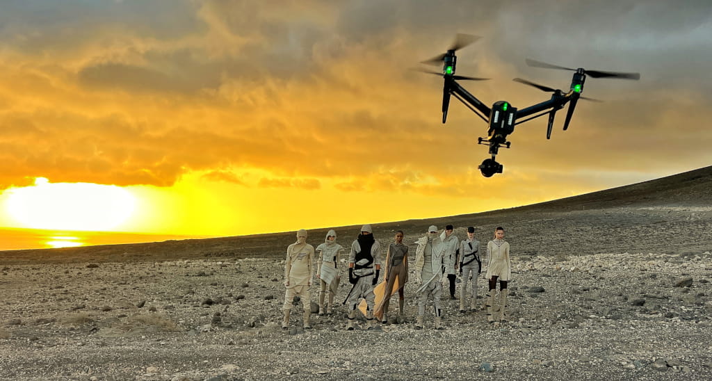 Group in futuristic costumes and a drone flying over a desert landscape in Tenerife.