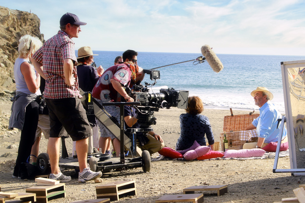 Film crew on a beach in Tenerife recording a scene with actors and picnic.