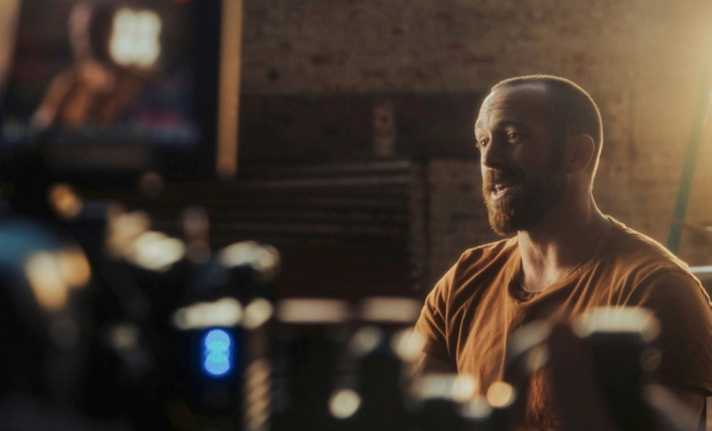 Person talking in front of cameras in a lit indoor environment.
