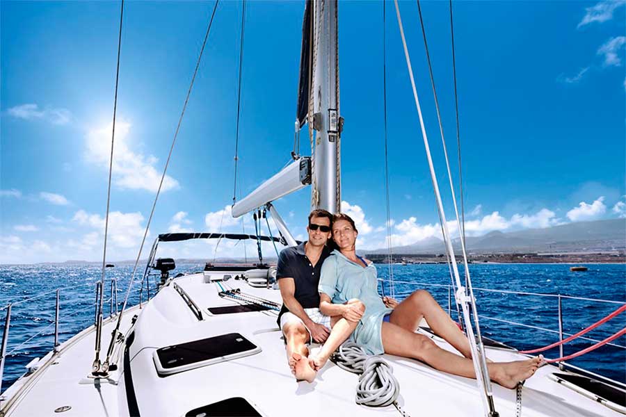 Couple sailing on a sailboat along the coast of Tenerife under a blue sky.