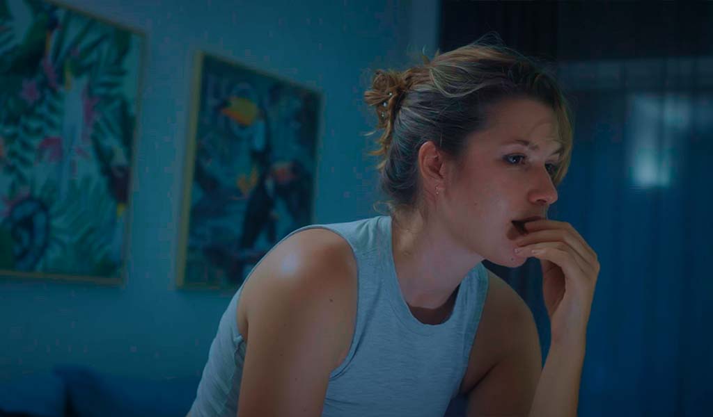 Thoughtful person observing something in a room with pictures on the walls.