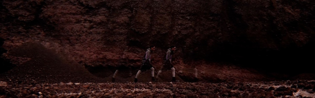 Person walks in front of a dark cliff in Tenerife.