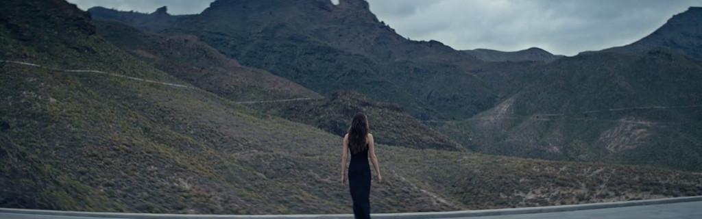 Person walking towards the mountains in Tenerife under a cloudy sky.