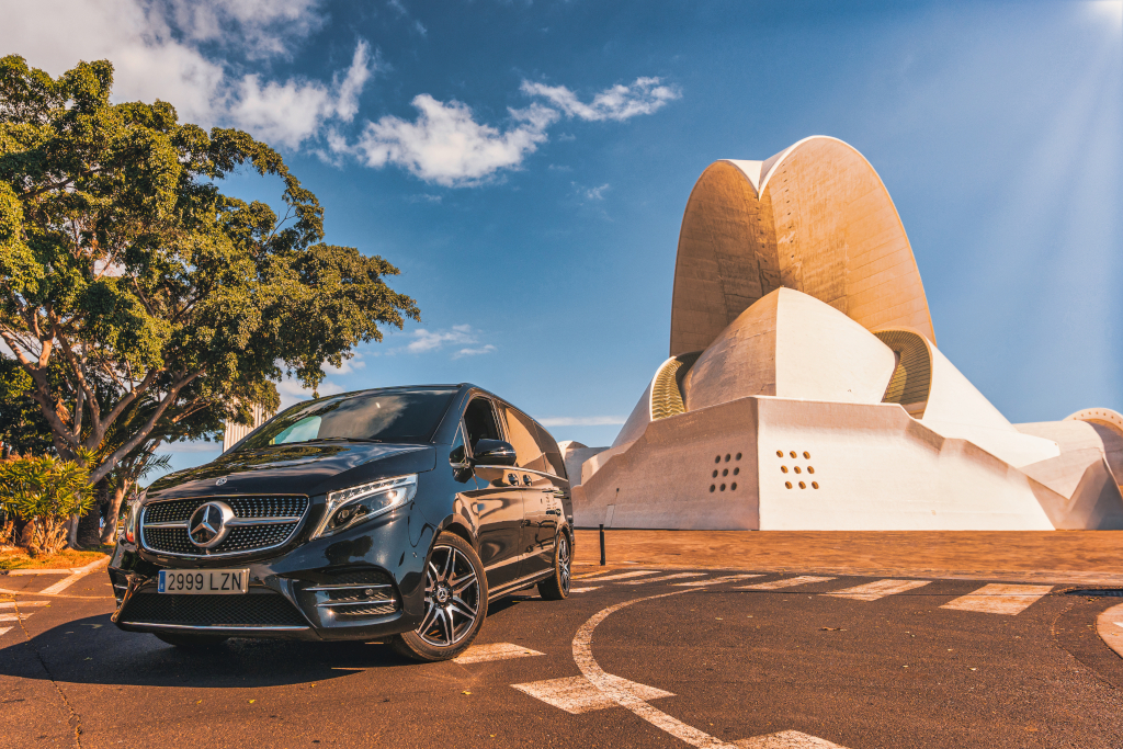 Black minivan in front of the Auditorio de Tenerife on a sunny day.