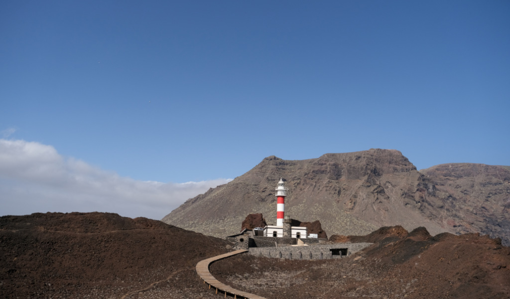 White and red lighthouse with a mountain backdrop in Tenerife.