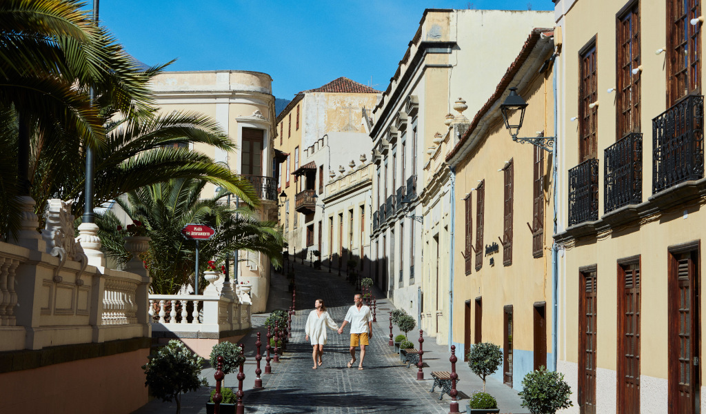People walking along a narrow street lined with colorful buildings in La Orotava.