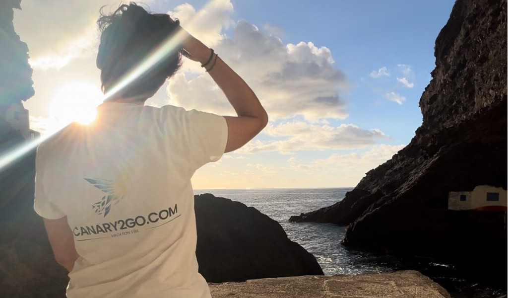 Person with CANARY2GO.COM shirt looking at sunset in Tenerife coast.
