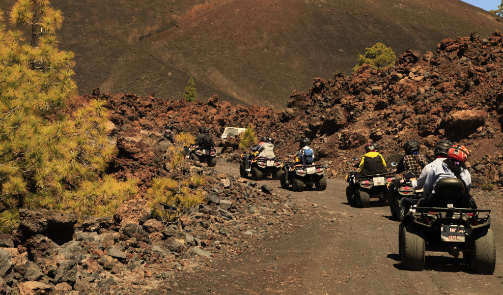 People riding ATVs on a rocky trail near Mount Teide, Tenerife.
