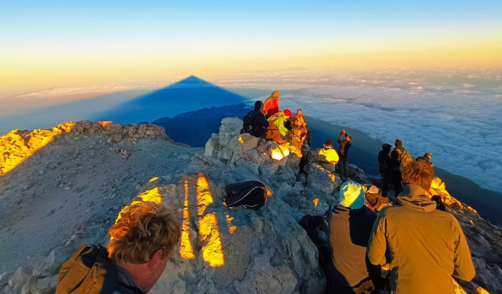 People watching sunrise from the peak of Mount Teide, Tenerife, above clouds.