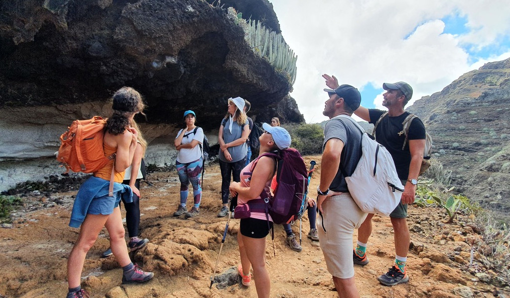 Hikers exploring rocky terrain in Tenerife, near a large rock formation.