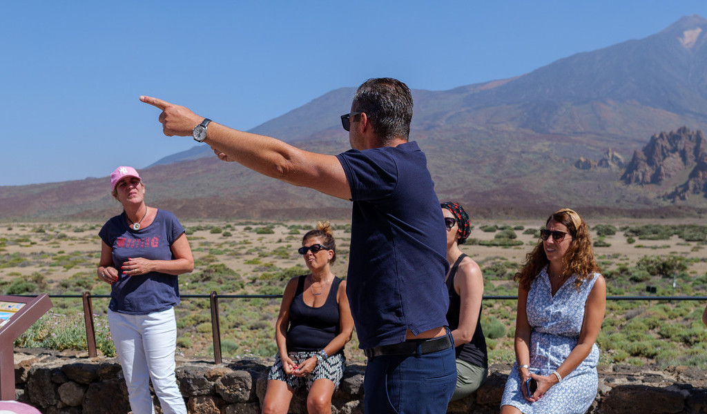 Group of people at Mount Teide viewpoint in Tenerife, with a man pointing.