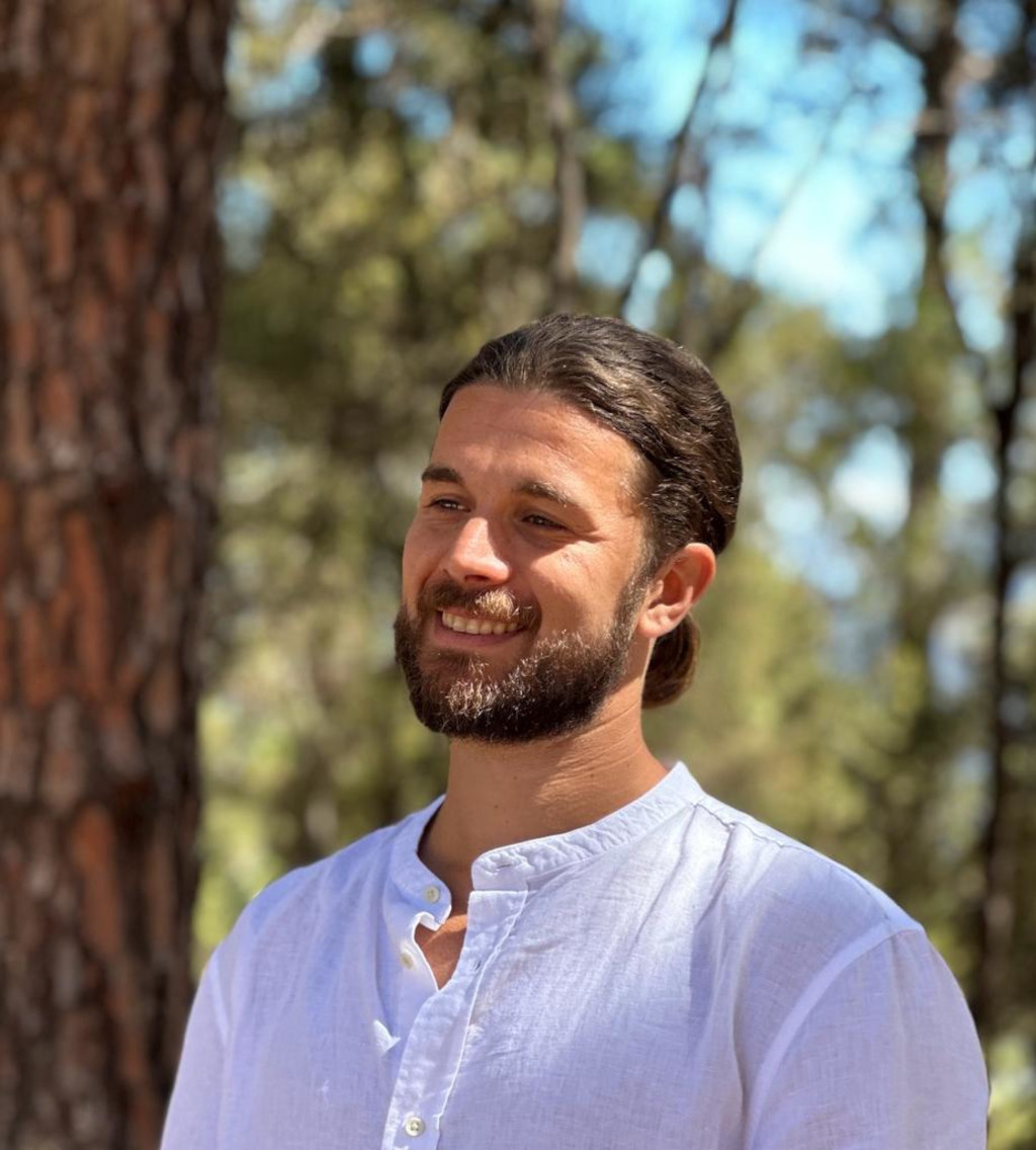A person in a white shirt smiling in a forest in Tenerife.