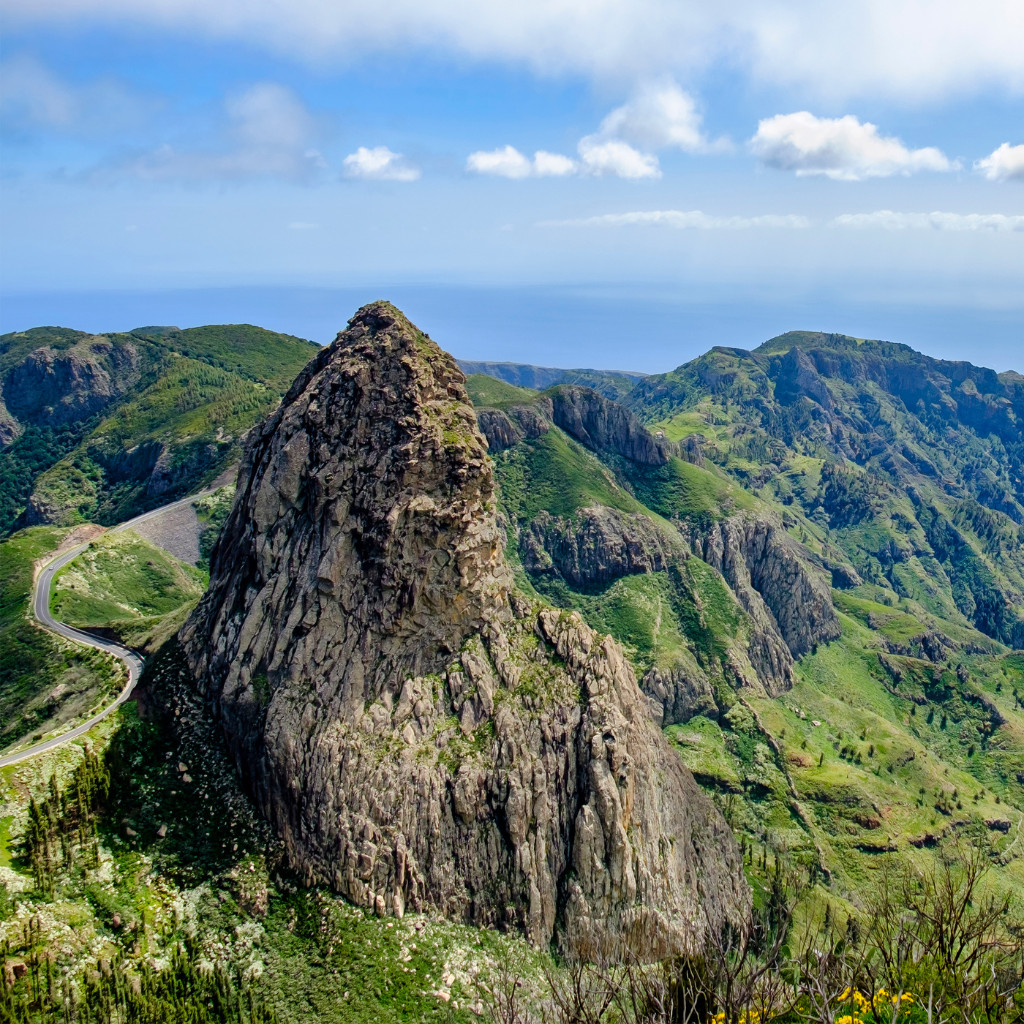 Roque de Agando in Tenerife with lush green mountains and blue sky in the background.