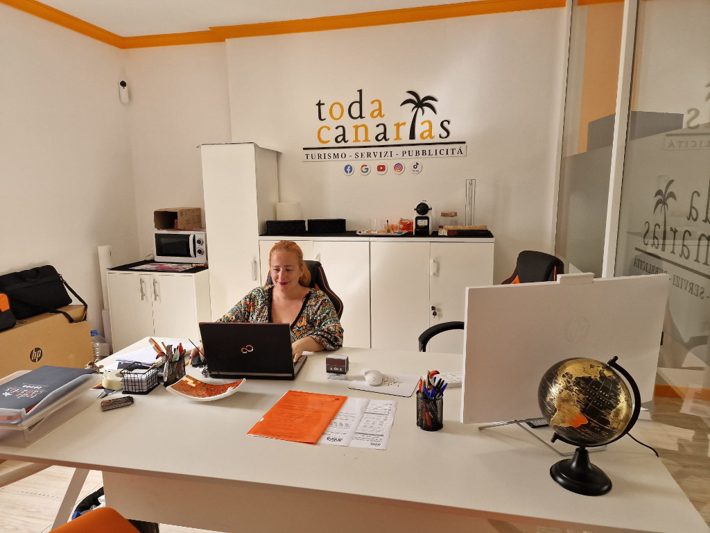 Woman working in the Toda Canarias office, with a computer and papers on the desk.