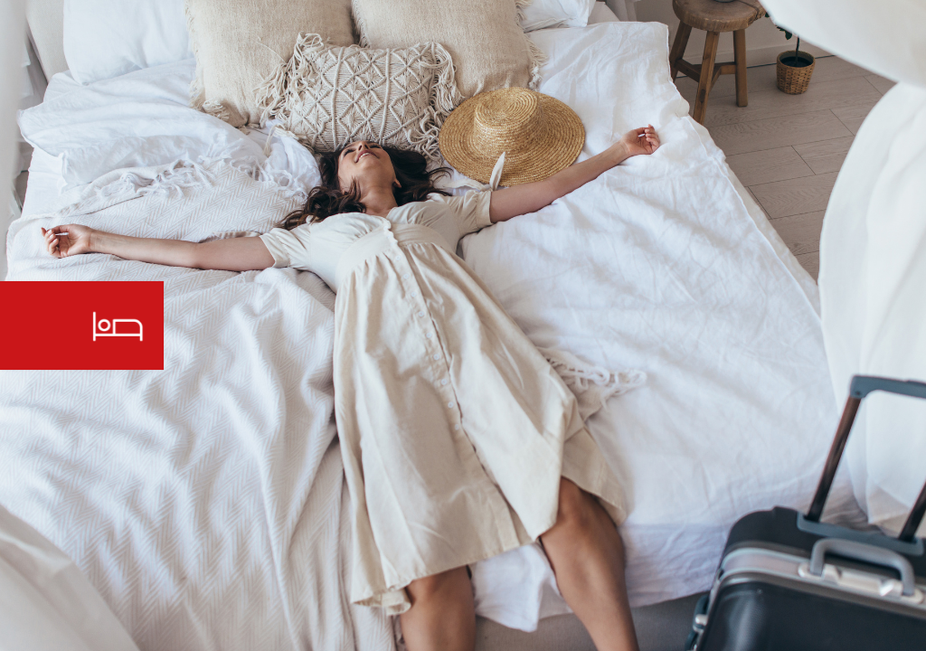 Person resting on a bed next to a suitcase and a hat in Tenerife.