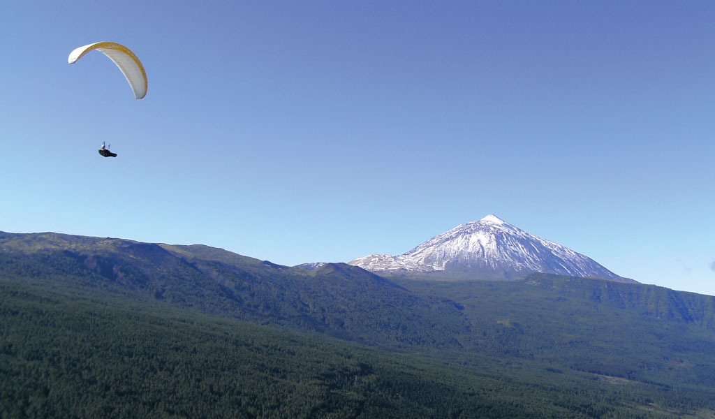 Paragliding over Mount Teide in Tenerife under a clear sky.