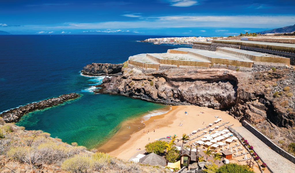 Beach with umbrellas and blue sea in Puerto de Santiago, Tenerife.