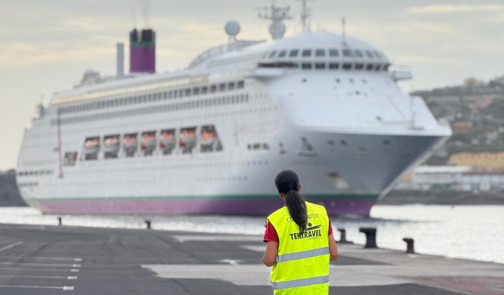 Person watching a cruise ship docked in the port of Tenerife. Vest says Coordinator Tentravel.
