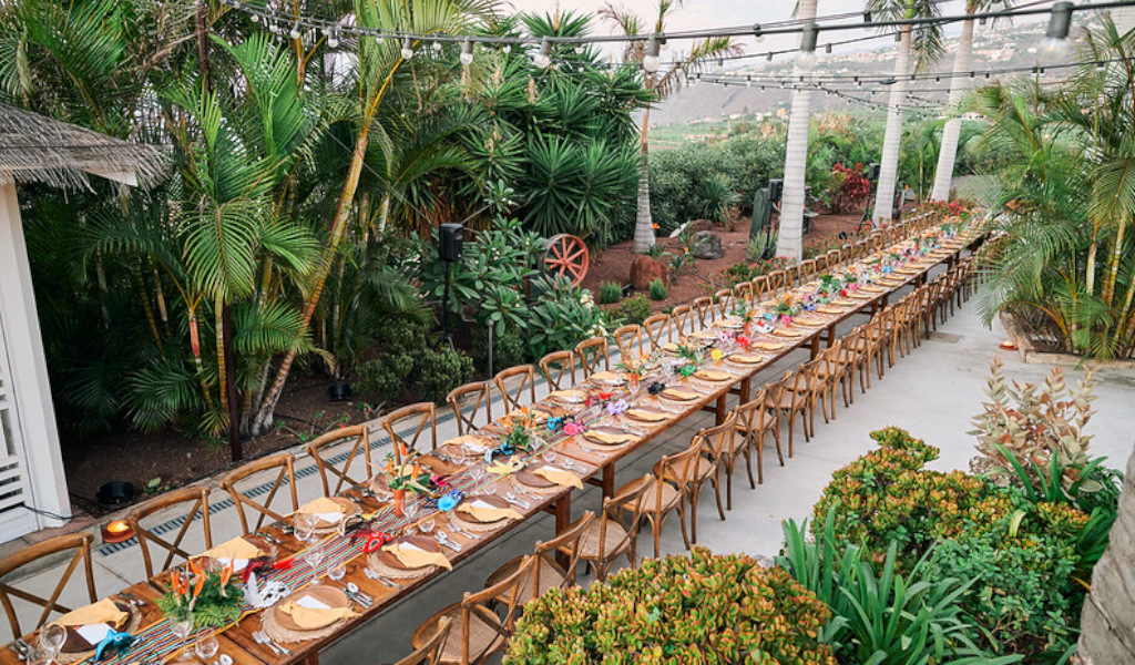 Long table decorated for outdoor events in Tenerife, surrounded by palm trees and vegetation.