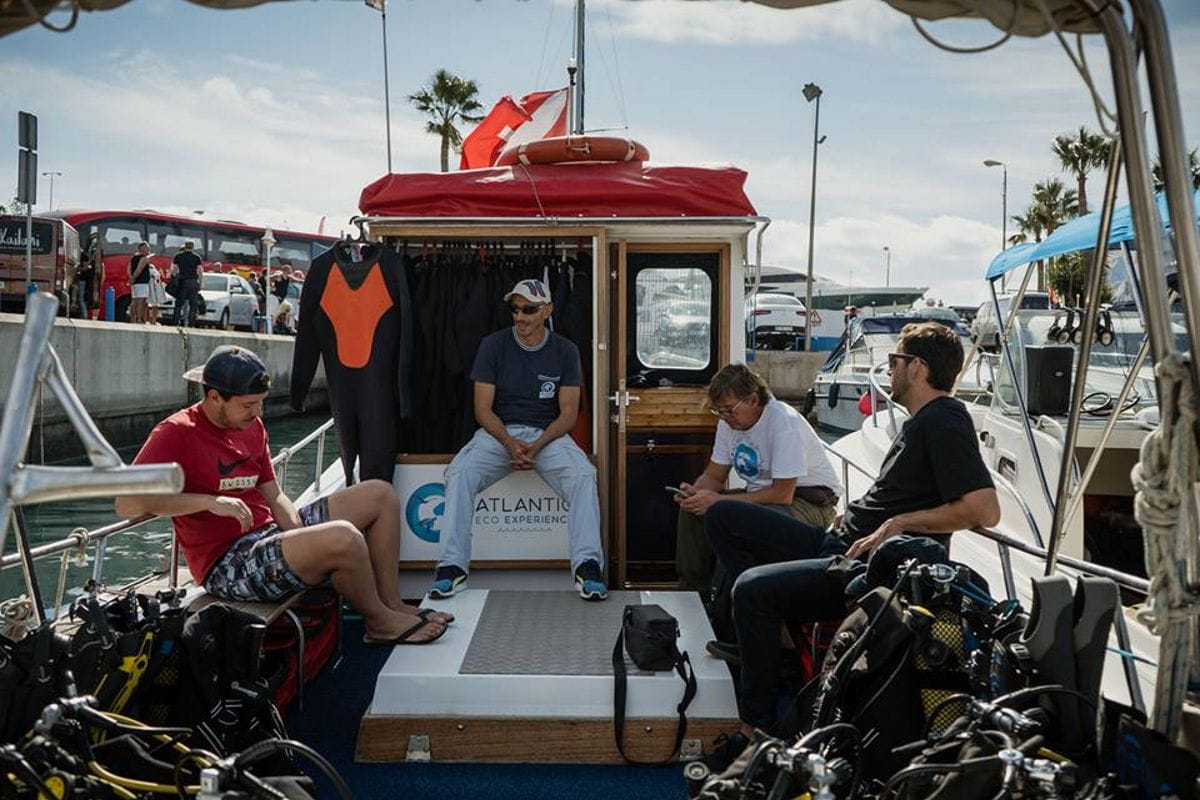 People sitting on a dive boat in Puerto Colon, Tenerife, wearing wetsuits.