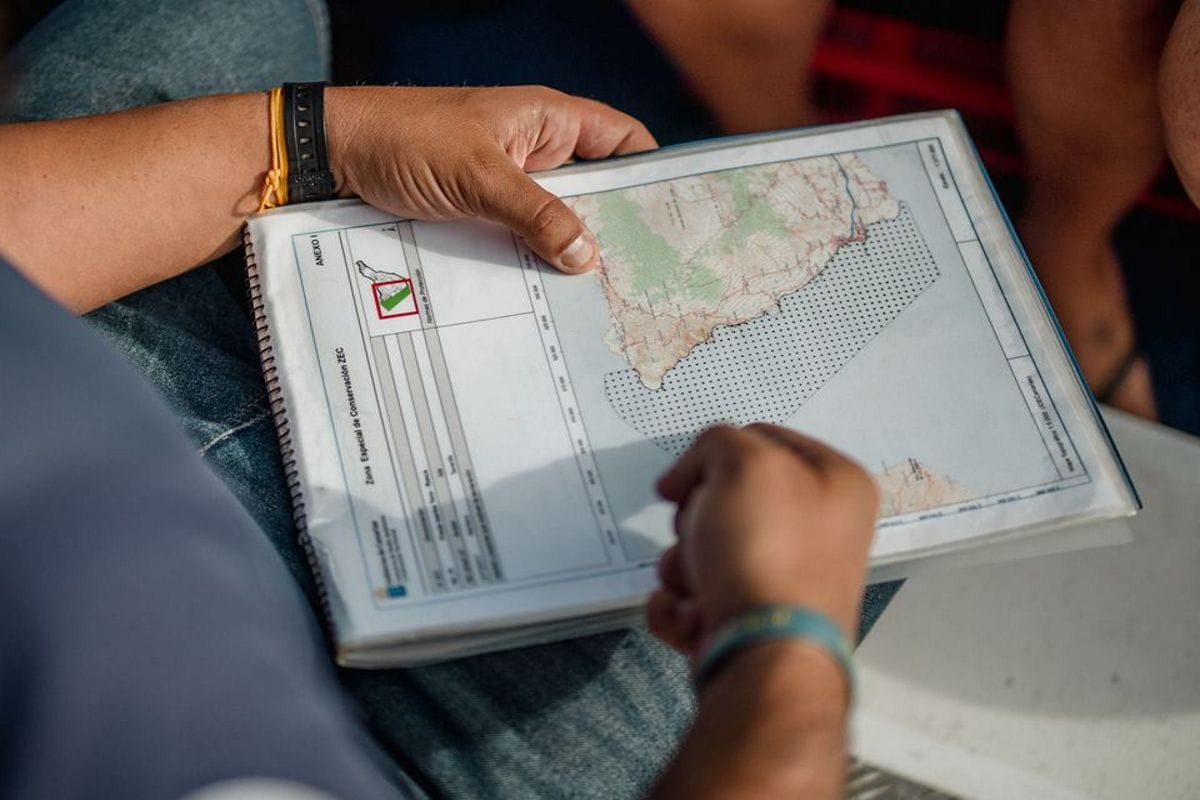 Person holding a map of Tenerife in a spiral notebook.