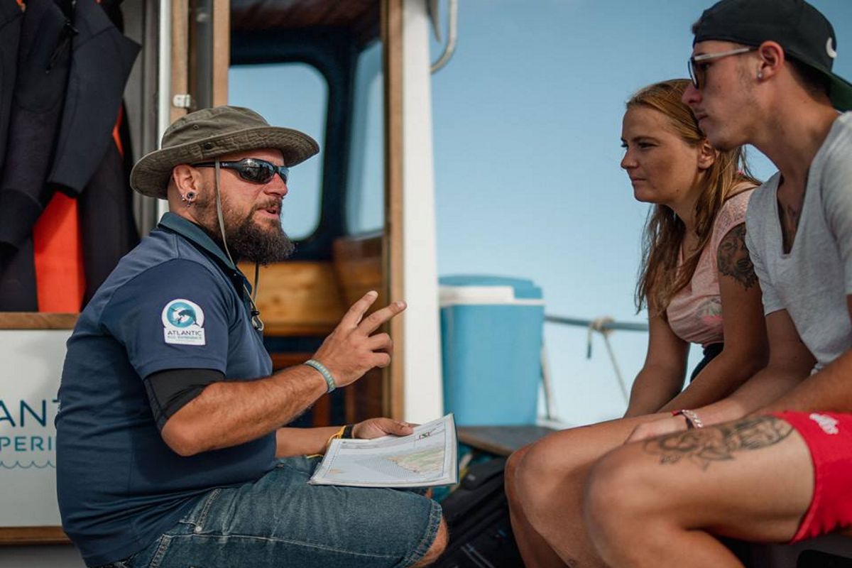 Guide explaining water activities in Tenerife to two people.