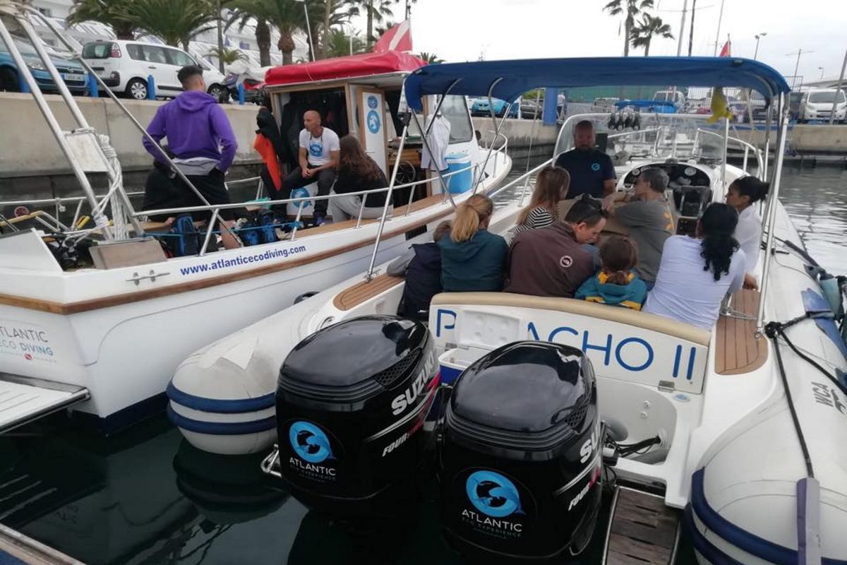 Group of people on a tourist boat in Tenerife, with Suzuki engines and Atlantic Eco Diving logo.