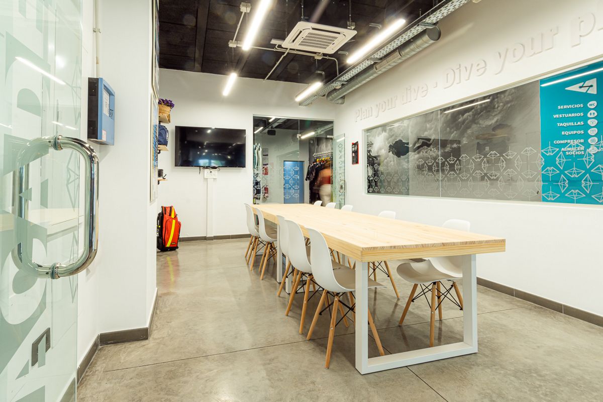 Meeting room with long table and white chairs in Tenerife dive center.