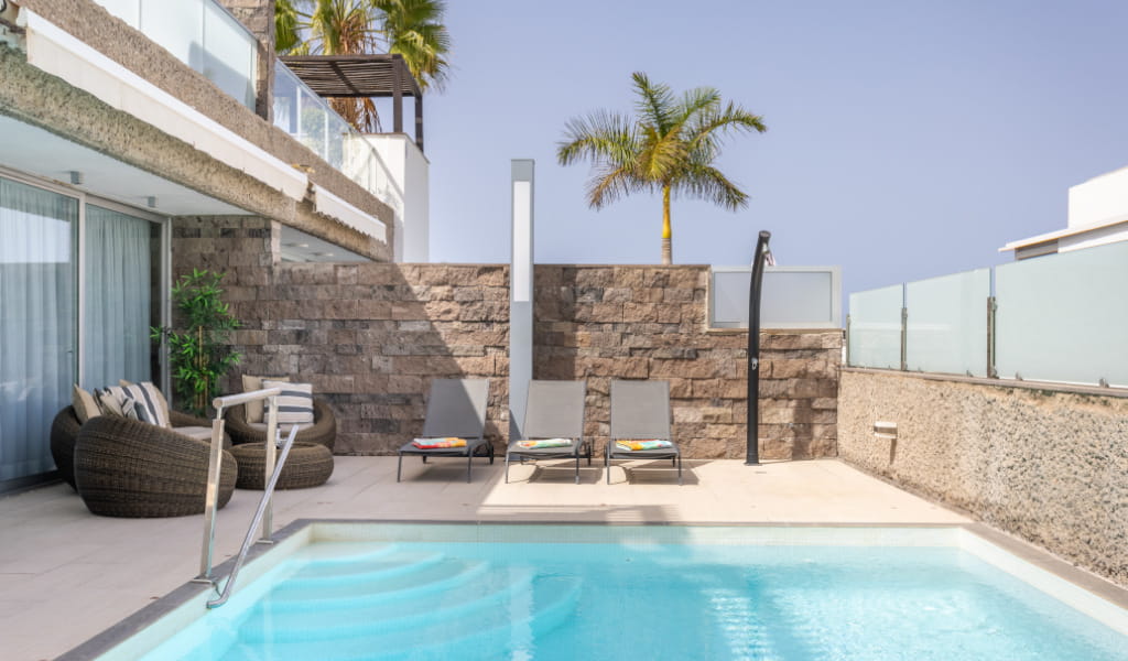 Outdoor swimming pool with chairs and palm tree in a hotel in Tenerife.