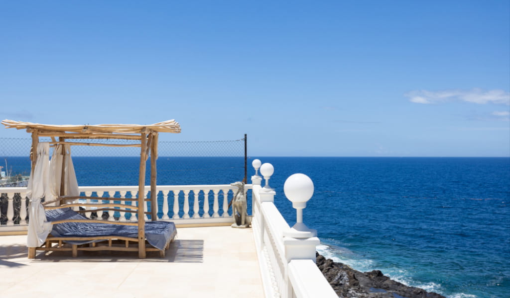 Wooden lounge chair facing the sea in Tenerife with clear skies.