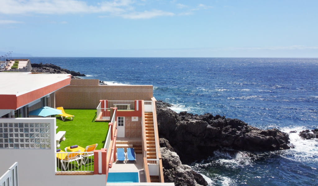 Terrace with lawn and sun loungers by the sea on a cliff in Tenerife.