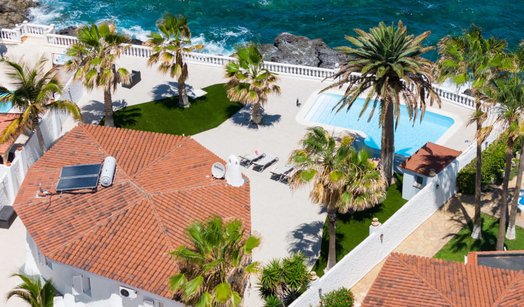 Aerial view of terrace with pool, palm trees and sea in Tenerife.