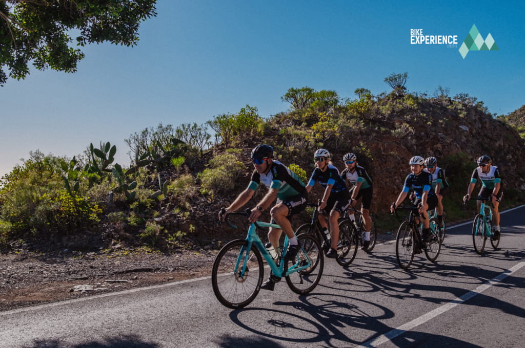 Cyclists on a mountainous route in Tenerife, with the Bike Experience logo.