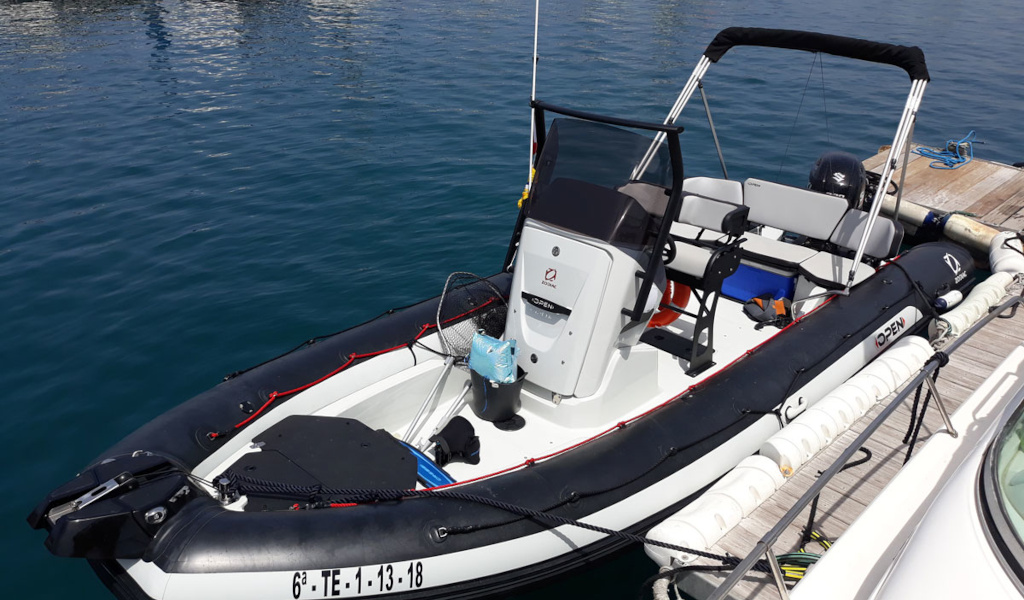Inflatable boat docked in the port of Tenerife, with seats and engine visible.