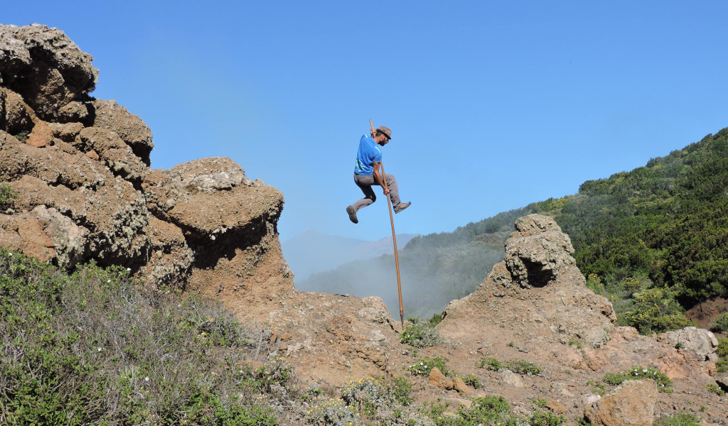 Person using a club to jump between rocks in a landscape of Tenerife.