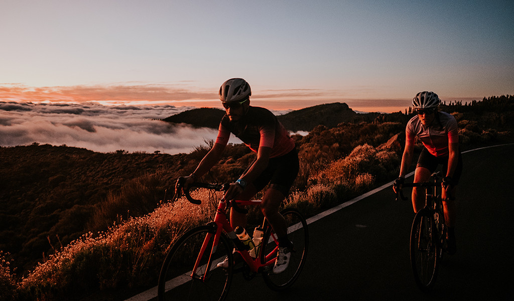 Road cyclists with mountainous landscape at sunset in Tenerife.