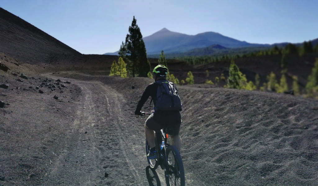Cyclist on a volcanic trail with Mount Teide in the background in Tenerife.