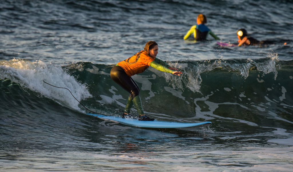Surfer on the beach in Tenerife riding a wave at sunset.