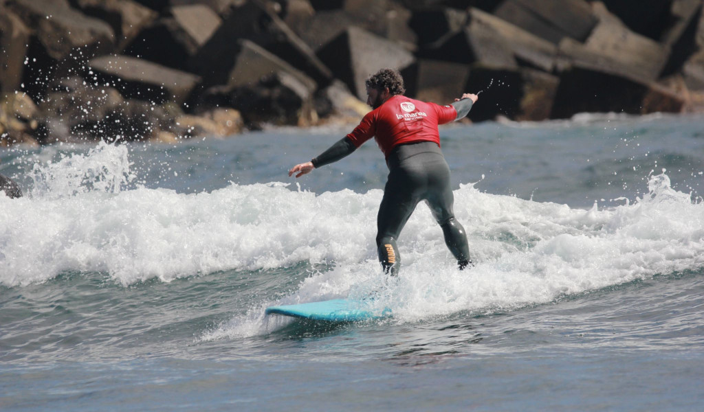Person surfing a small wave in the sea of Tenerife.