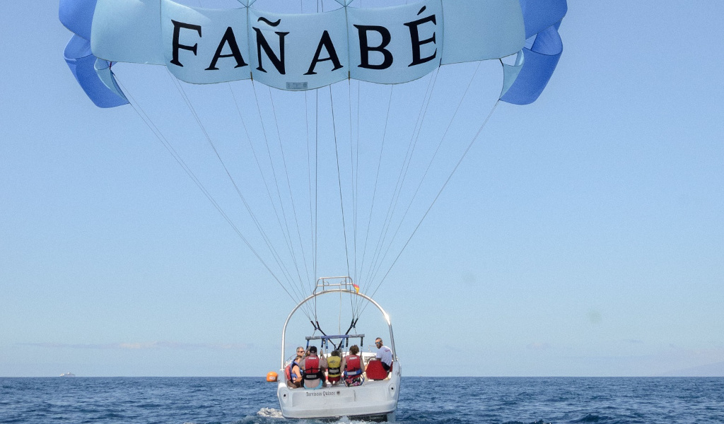 People parasailing in Fañabé, Tenerife, over the sea.