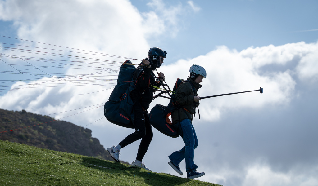 Two people taking off in paragliding in Tenerife under a cloudy sky.